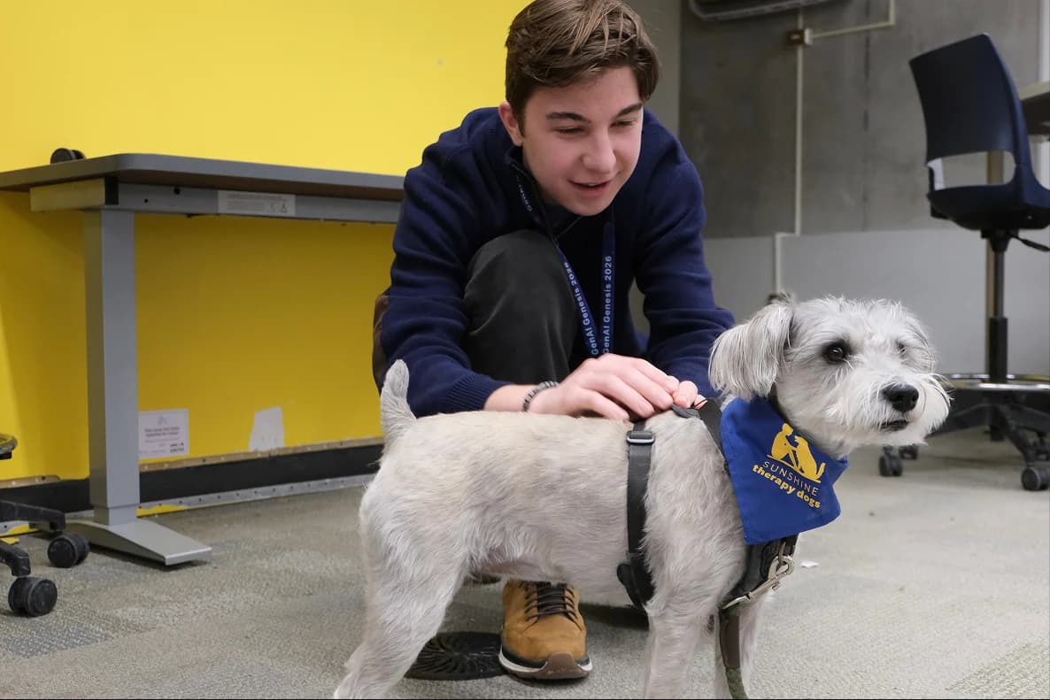 A hacker petting a therapy dog during GenAI Genesis